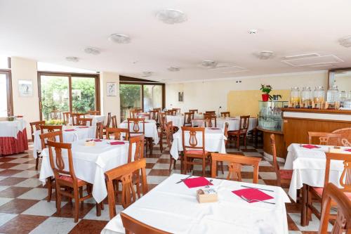 a restaurant with white tables and wooden chairs at Hotel Russo Palace in Venice-Lido