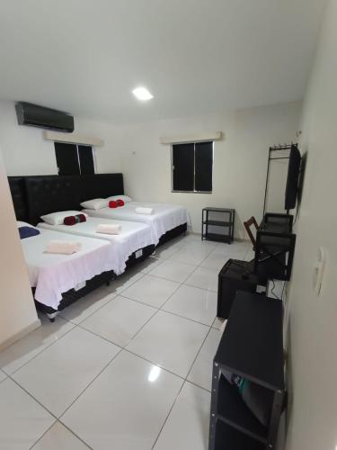 a bedroom with two beds and a television in it at Bendita Parada - Pousada in Sobral