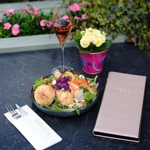 a bowl of salad and a glass of wine on a table at Boutique Hotel Venlo in Venlo