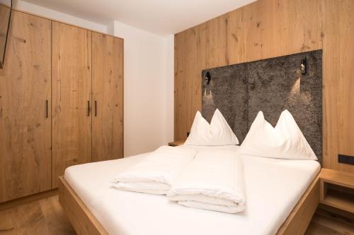 a bedroom with a white bed with wooden cabinets at Berghotel Alpenklang in Grossarl