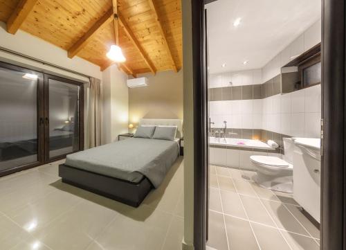 a bedroom with a bed and a sink and a toilet at Eden Villas in Anafonítria