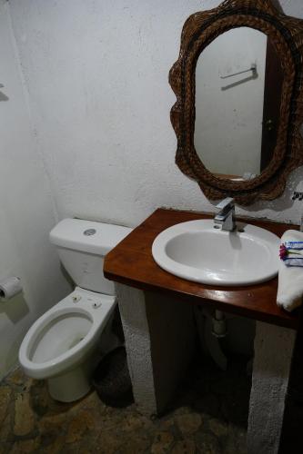 a bathroom with a toilet and a sink with a mirror at Eco Hotel Sak Nok in Lacanjá