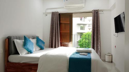 a bedroom with a bed with blue pillows and a window at Zenith Suites & Service Apartments - Powai in Mumbai