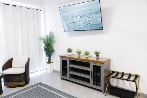 a living room with a tv and a white wall at Vista Pedregal-Stylish Holiday Apartment in the Heart of Cabo, 2 Minutes walk to Marina in Cabo San Lucas