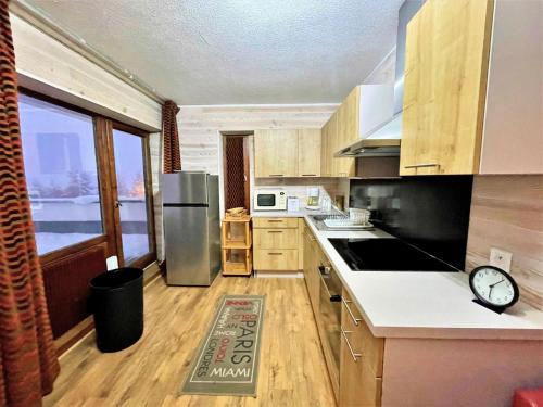 une cuisine avec un réfrigérateur en acier inoxydable et des armoires en bois dans l'établissement Résidence Oisans - Grand appartement pour 8 personnes aux pieds des pistes MAE-4011, aux Menuires
