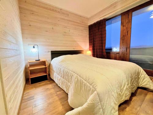 - une chambre avec un grand lit et une cheminée dans l'établissement Résidence Oisans - Grand appartement pour 8 personnes aux pieds des pistes MAE-4011, aux Menuires