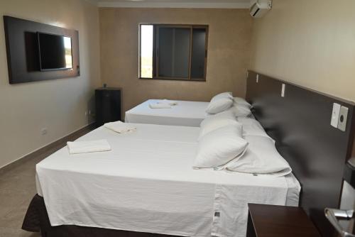 a bedroom with two beds with white sheets and pillows at Master Gold Hotel Express in Cascavel