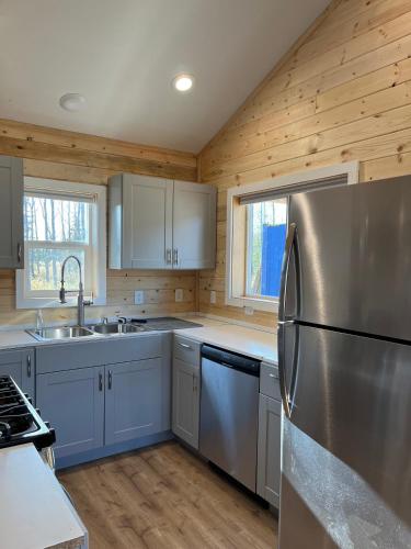 a kitchen with a stainless steel refrigerator and wooden walls at Kenai Adventure Cabins in Soldotna