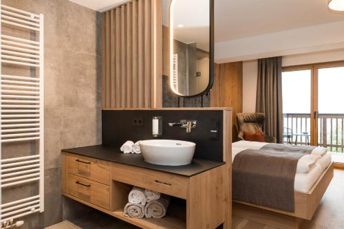 a bathroom with a sink and a bed and a mirror at Berghotel Alpenklang in Grossarl