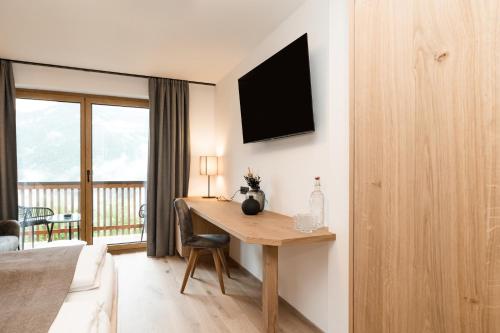 a room with a desk with a television on the wall at Berghotel Alpenklang in Grossarl