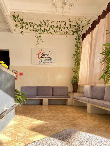 a waiting room with couches and plants on the wall at Hotel Avenida Bauru in Bauru