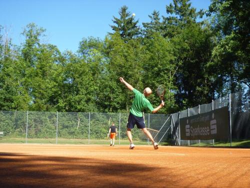 a man holding a tennis racket on a tennis court at KopfRausch Appartements in Feldkirch