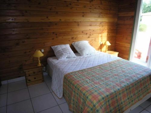 a bedroom with a bed and a wooden wall at Résidence 03134-lacanau Ocean - Chalet bois indépendant, 3 chambres, 6 personnes proche plage Lacanau océan MAE-0531 in Lacanau