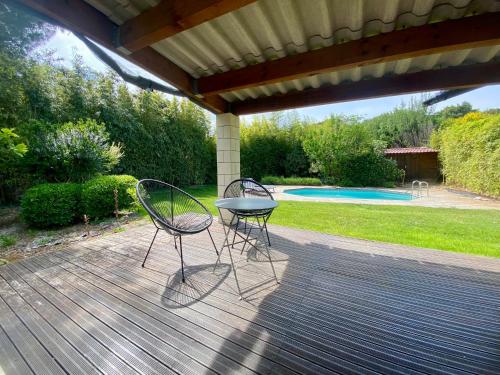 deux chaises et une table sur une terrasse en bois dans l'établissement Villa de vacances nichée dans la Garrigues, à 10 minutes d'Avignon, à Villeneuve-lès-Avignon