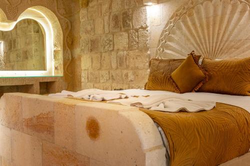a bed in a room with a stone wall at Lagoon Cave Suites in Urgup