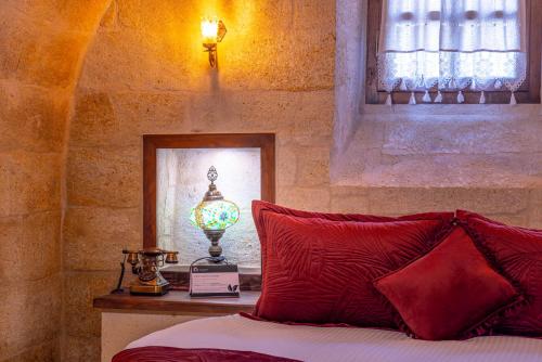 a bedroom with a bed with red pillows and a lamp at Lagoon Cave Suites in Urgup