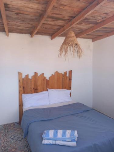 a bedroom with a blue bed with a wooden headboard at EL Faro Surfstay in Tamri