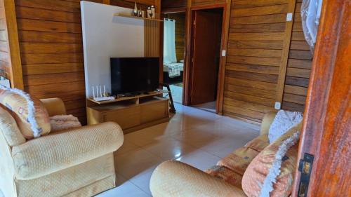 ein Wohnzimmer mit zwei Stühlen und einem Fernseher in der Unterkunft Eco Cabana Mantiqueira in Queimada