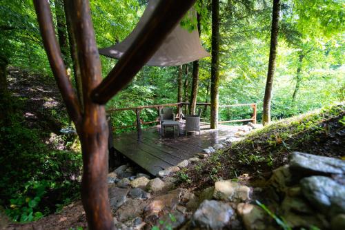 a wooden deck with two chairs on it in the woods at Holiday house Kajfes in Brod na Kupi