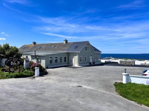 a house with a large driveway in front of the ocean at Coach House Lodge in Lahinch