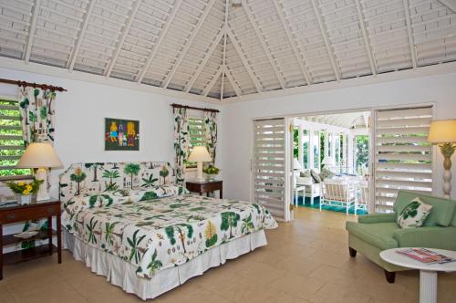 a bedroom with a bed and a green chair at Round Hill Hotel & Villas in Montego Bay