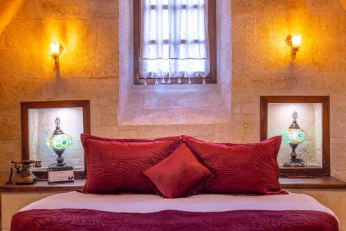 a bedroom with a bed with red pillows and two windows at Lagoon Cave Suites in Urgup