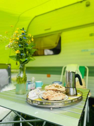 a table with a plate of food and a vase with flowers at Cute little caravan for 2 in old orchard in Hem