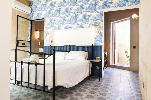 a bedroom with a bed with blue wallpaper at Fourteen Guesthouse in Żejtun