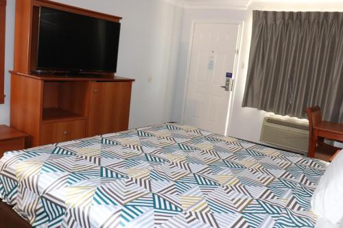 a bedroom with a bed and a flat screen tv at Motel 6-Alvin, TX in Alvin