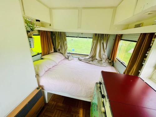a bedroom with a bed in an rv at Cute little caravan for 2 in old orchard in Hem