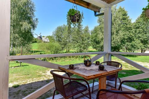 a table and chairs on a porch with a view of a field at Kempingas Prie Vencavų malūno in Viencavai