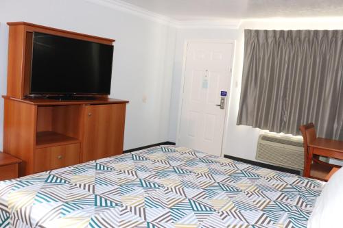 a bedroom with a bed and a flat screen tv at Motel 6-Alvin, TX in Alvin