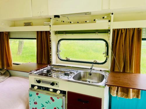 a kitchen with a sink and a stove at Cute little caravan for 2 in old orchard in Hem