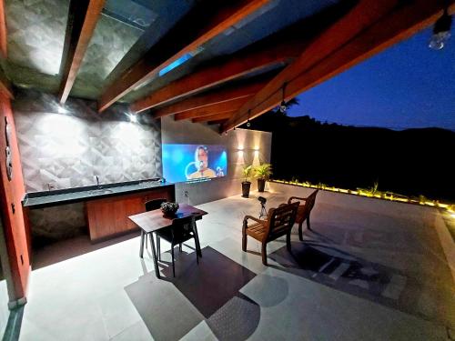 a patio with a table and chairs and a television at Recanto Lua de Lumiar in Nova Friburgo