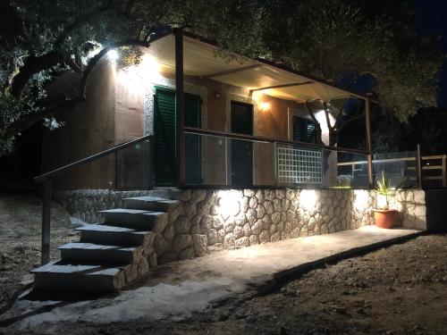 a house with a stone wall and stairs at night at Villa MaryElen Marathias beach in Corfu Town