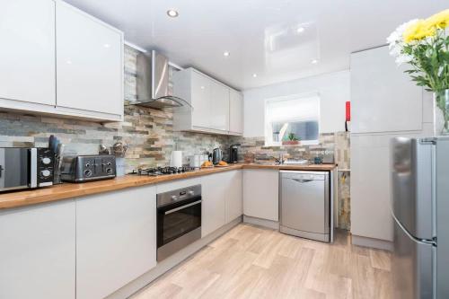 eine Küche mit weißen Schränken und Geräten aus Edelstahl in der Unterkunft Central Saltburn 2 bed family apartment in Saltburn-by-the-Sea