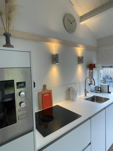 a kitchen with a sink and a stove top oven at Strandhuisje Anna dicht bij de zee in Ouddorp