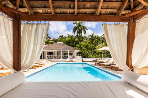 an outdoor pool with chairs and a pavilion at Round Hill Hotel & Villas in Montego Bay