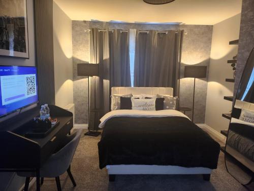 Un dormitorio con una cama, un escritorio y un televisor. en Eden Suite, en Stockton-on-Tees