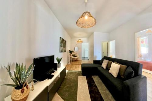 a living room with a black couch and a tv at Madeira Breeze in Funchal