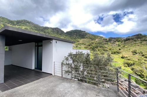 a house with a balcony with mountains in the background at Sal e Pimenta House - A Wellbeing Retreat in Machico