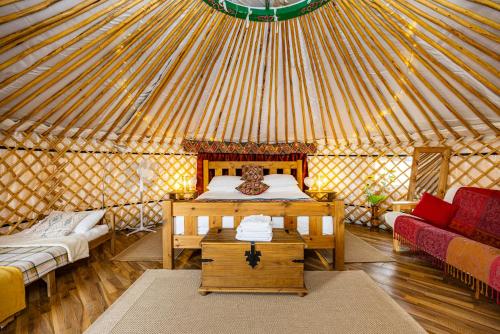 a yurt with a bed and two couches in it at Meadow Vale Retreats in Screveton
