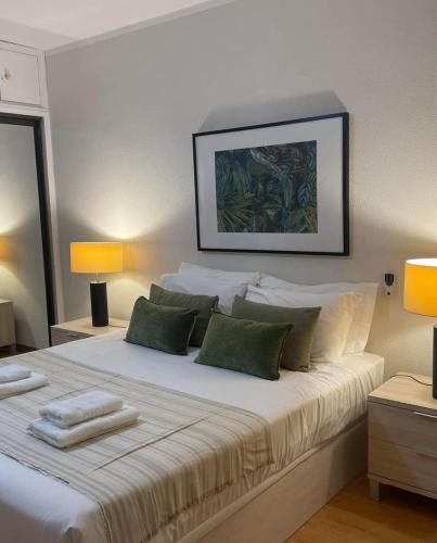 a bedroom with a large white bed with green pillows at Mar Sereno Praia Formosa in Funchal