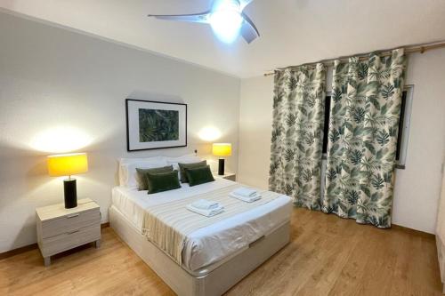 a bedroom with a bed and two lamps and a window at Mar Sereno Praia Formosa in Funchal