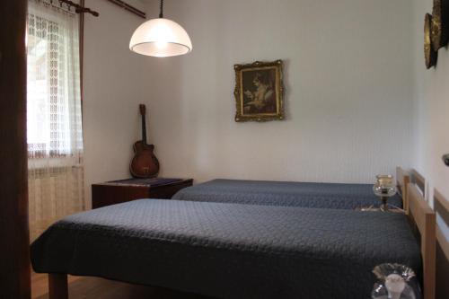 a bedroom with two beds and a guitar on the wall at Boulevard Garden House - Free and save parking in the locked yard in Ćuprija