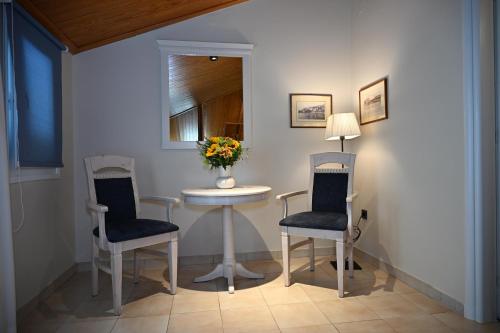 a room with two chairs and a table with a vase of flowers at Porto Nafplio in Nafplio