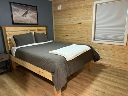 a bed in a bedroom with a wooden wall at Kenai Adventure Cabins in Soldotna