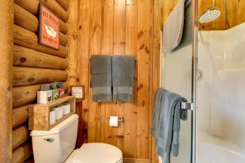 a bathroom with wooden walls and a toilet and a shower at Near Fishing and Hiking Pinetop Log Cabin with Deck! in Pinetop