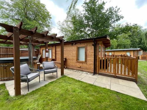 a house with a pergola and two chairs in a yard at Lakeside Lodge 1, with Log burning Hot Tub in Everton