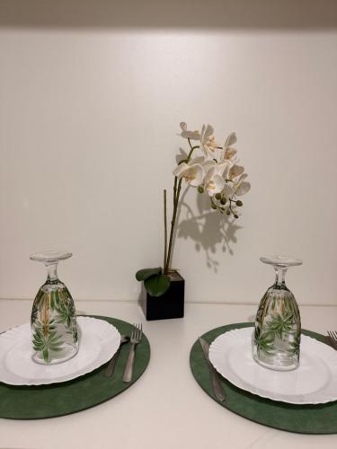 two vases sitting on plates on a table with a plant at Suíte Privativa in Florianópolis